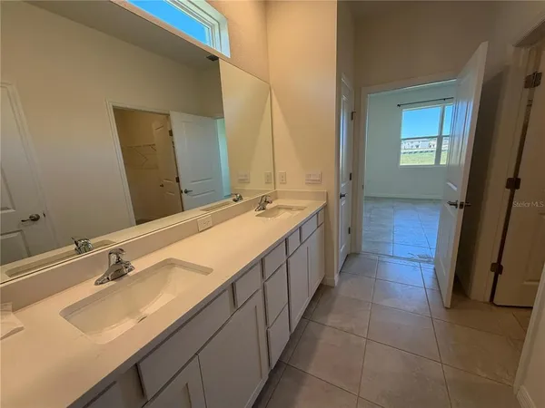 a spacious bathroom with a double vanity sink a mirror and a bathtub