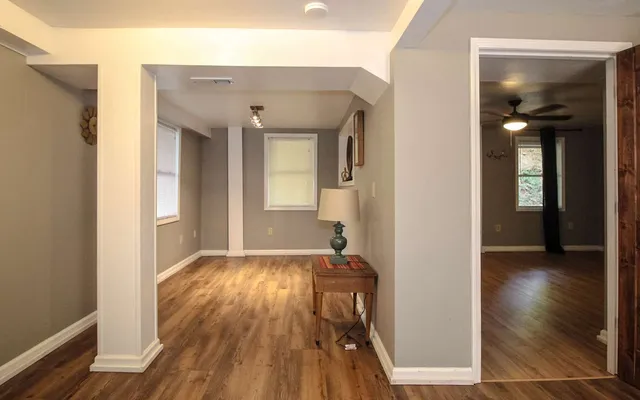 a view of a hallway with wooden floor and a bathroom