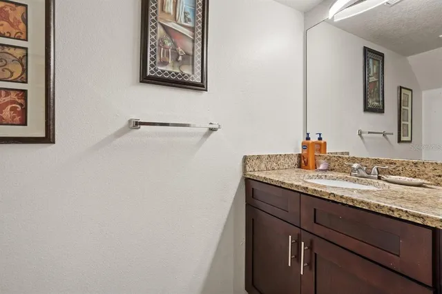 a bathroom with a granite countertop sink a mirror and vanity
