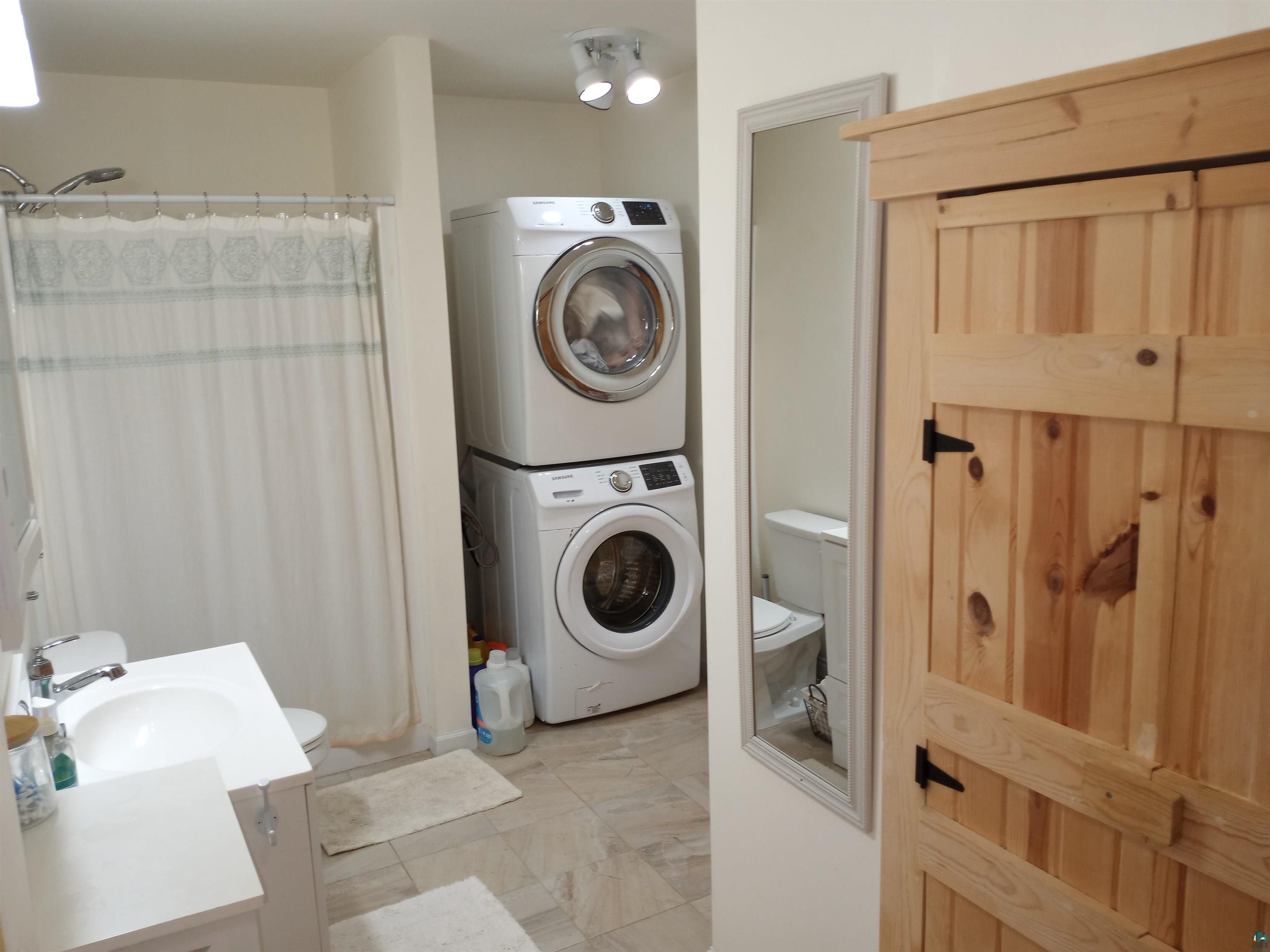 88525 Romans Point Road Herbster, WI 54844 - Photo 14 of 14 Laundry area featuring sink, stacked washer and dryer, and light tile patterned floors