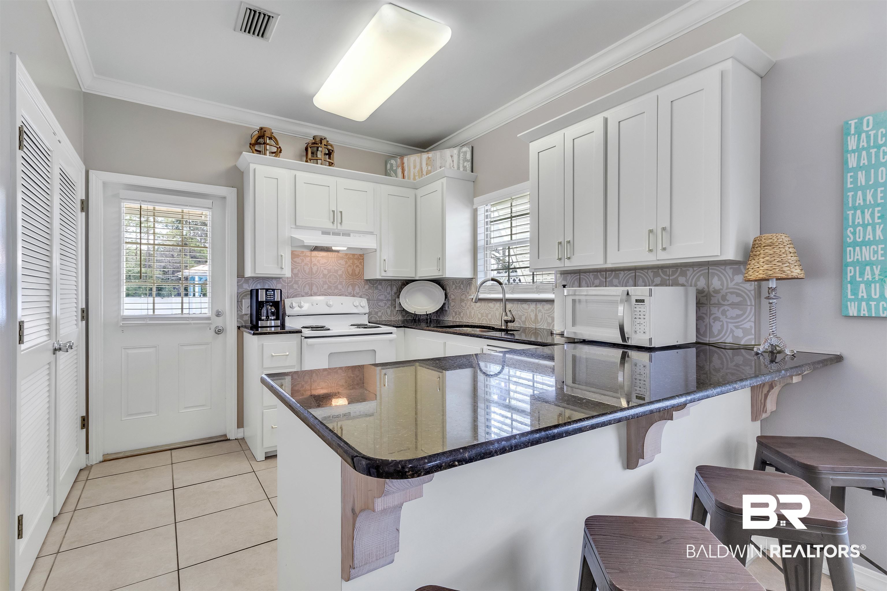 4324 B Lindsey Lane, Unit 4324B Orange Beach, AL 36561 - Photo 3 of 33 Kitchen with white appliances, white cabinets, a peninsula, under cabinet range hood, and a sink