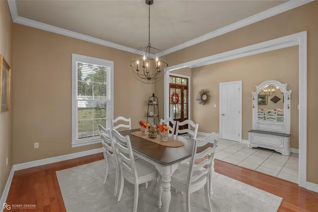 a dining room with chandelier and wooden floor