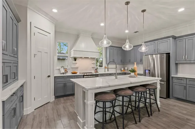 a kitchen with stainless steel appliances granite countertop a sink a stove a refrigerator and island with wooden floor