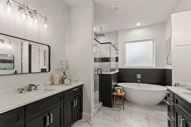 a bathroom with a tub a sink double vanity and mirror