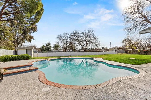 a view of a swimming pool with a yard and plants