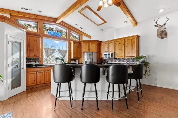 a kitchen with stainless steel appliances kitchen island granite countertop a table chairs in it and wooden floors