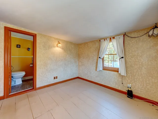 a view of an empty room with window and a bathroom