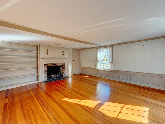 a view of empty room with wooden floor and fireplace