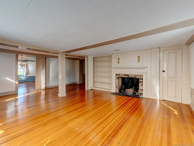 a view of empty room with wooden floor and fireplace