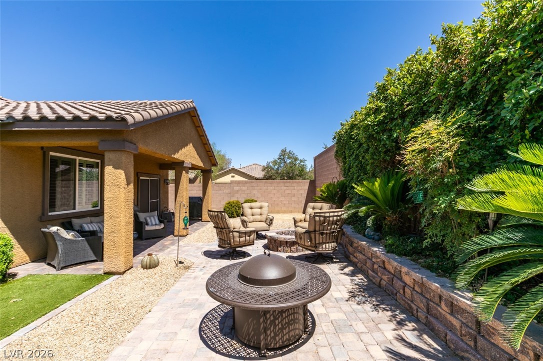 7375 Campbell Ranch Avenue Las Vegas, NV 89179 - Photo 32 of 45 An inviting outdoor oasis with a covered patio, paved fire pit area, and lush landscaping for relaxation.