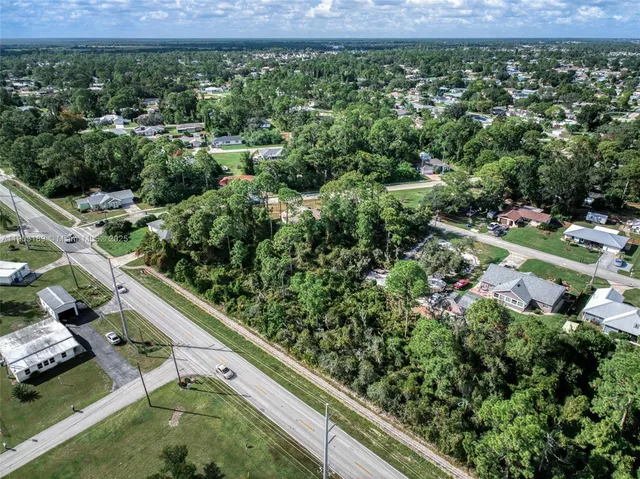 an aerial view of residential houses with outdoor space and trees