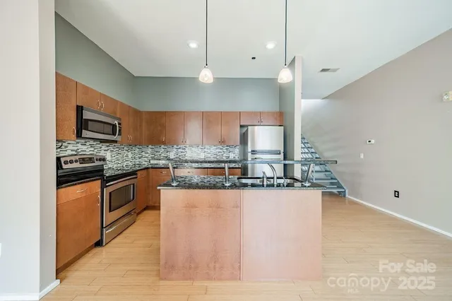 a large kitchen with stainless steel appliances kitchen island granite countertop a sink and a stove