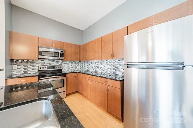 a kitchen with granite countertop a refrigerator and a stove top oven