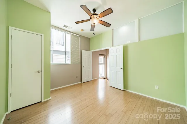 a view of an empty room with window and wooden floor