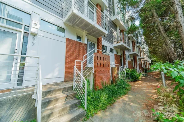 a pathway of a house with a yard and balcony