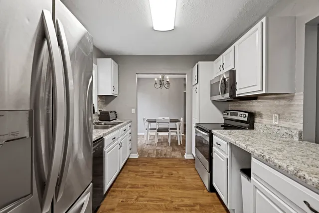 a kitchen with stainless steel appliances granite countertop a refrigerator a stove and a sink