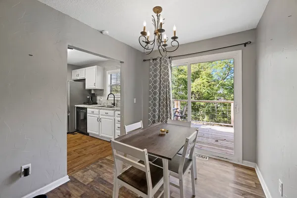 a dining room with wooden floor a chandelier a wooden table and chairs