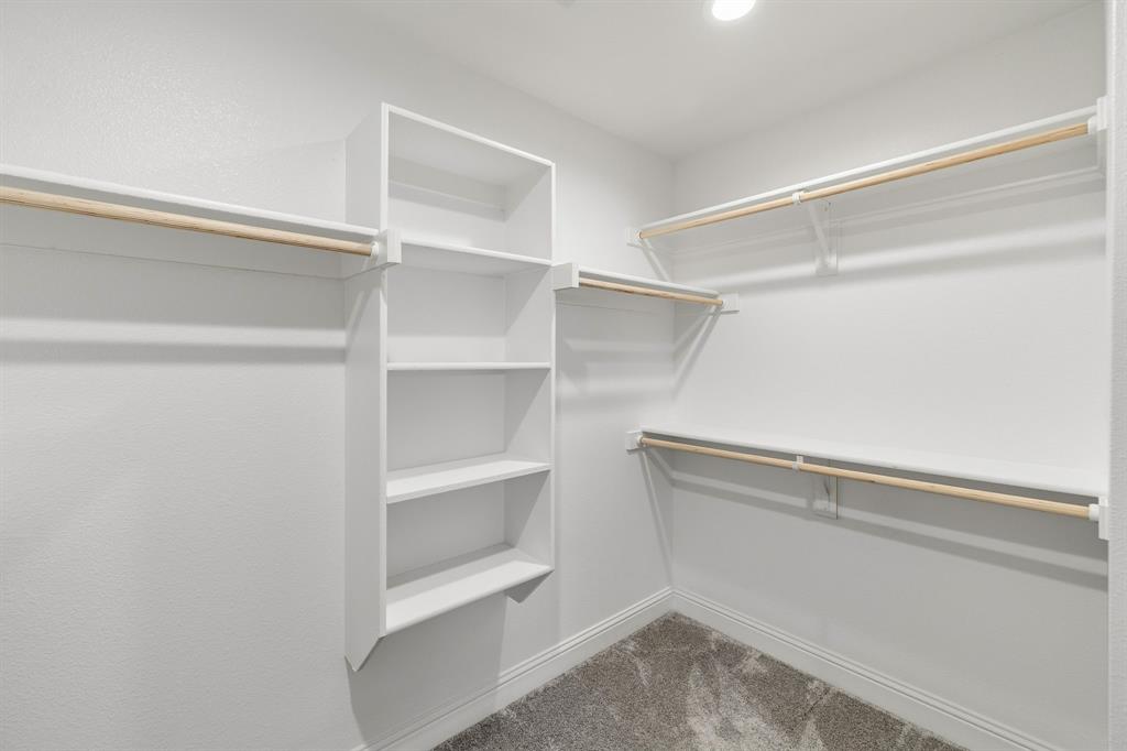 915 Timber Ridge Drive Justin, TX 76247 - Photo 25 of 39 Walk-in closet featuring white built-in shelving, multiple hanging rods, recessed lighting, and textured carpeting