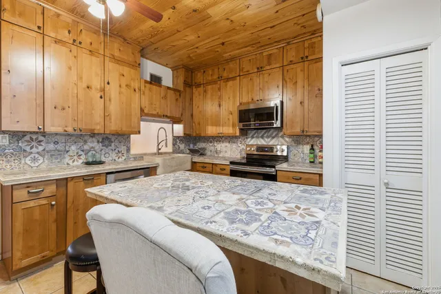 a kitchen with stainless steel appliances granite countertop a sink stove refrigerator and cabinets