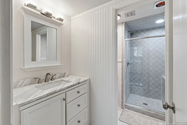 a bathroom with a shower sink vanity and mirror