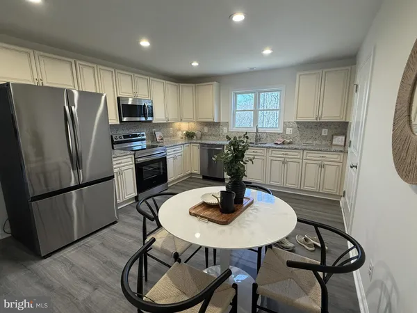 a kitchen with stainless steel appliances granite countertop a sink a stove a refrigerator cabinets and dining table