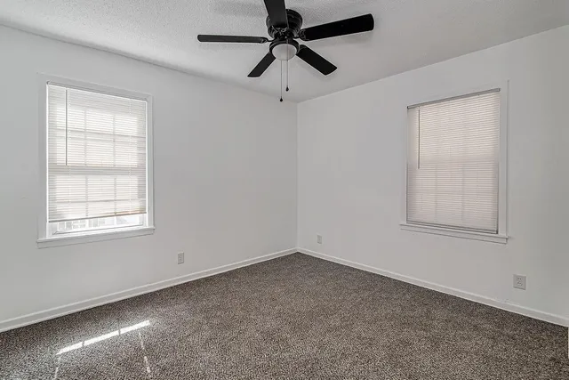 an empty room with a window and a fan