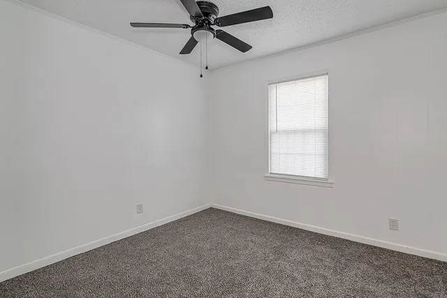 an empty room with a window and a fan