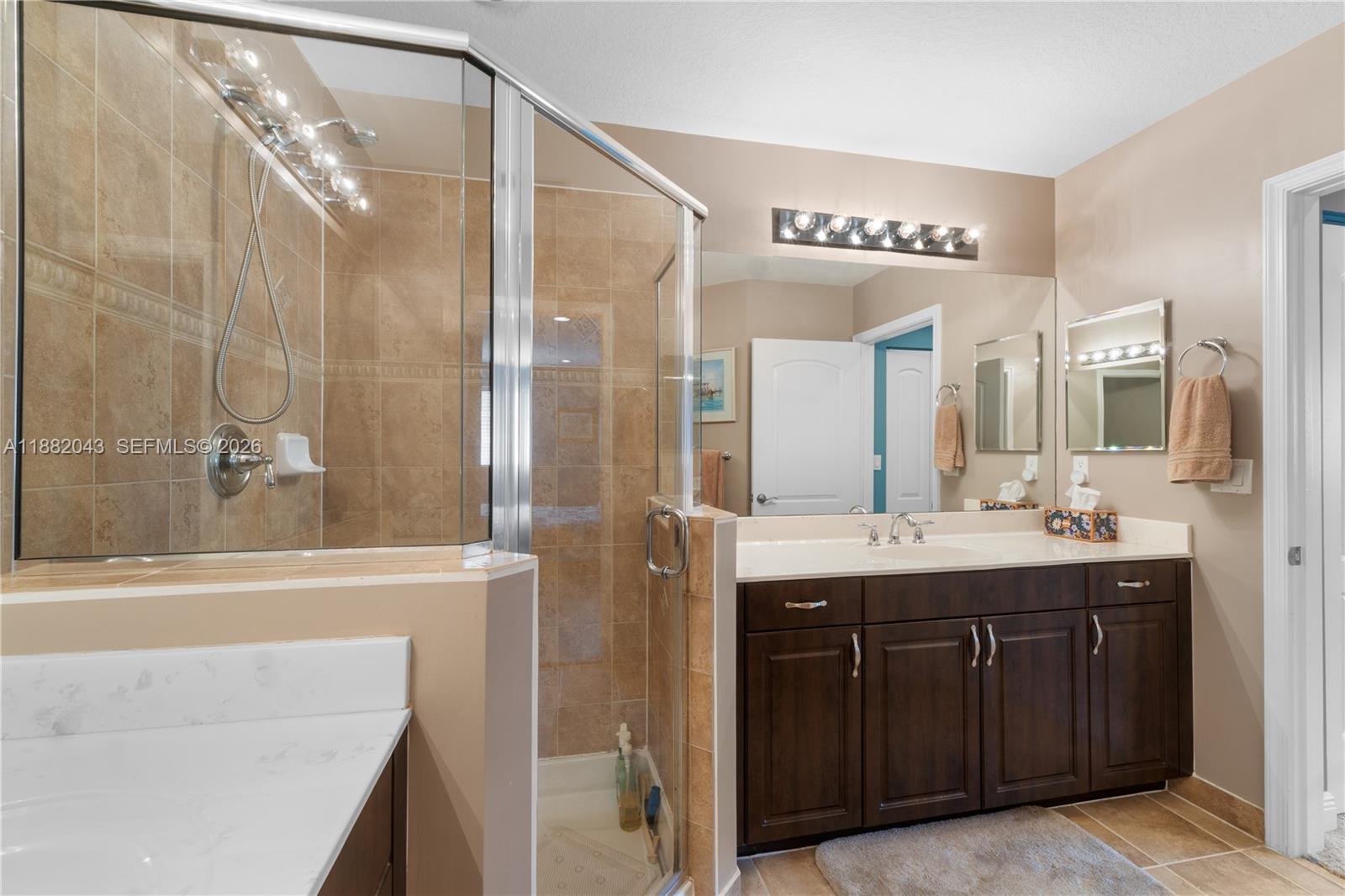 7702 Paddock Place, Unit 7702 Davie, FL 33328 - Photo 14 of 55 a bathroom with a granite countertop sink a mirror and a shower
