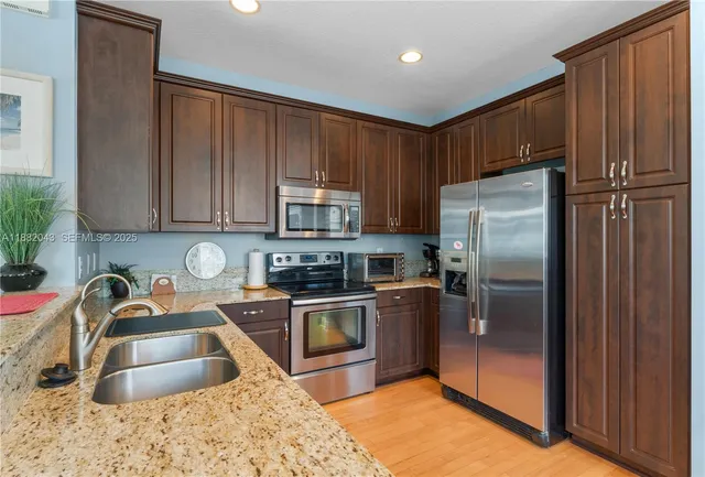 a kitchen with granite countertop a refrigerator sink and stainless steel appliances