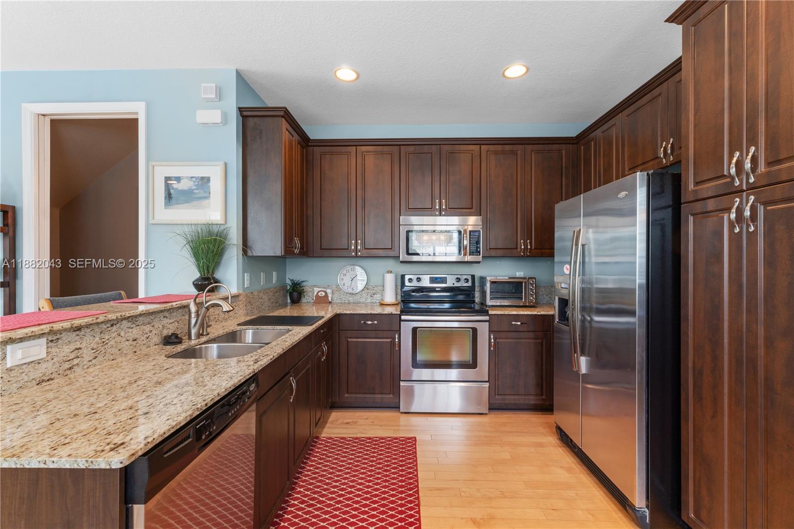 7702 Paddock Place, Unit 7702 Davie, FL 33328 - Photo 34 of 55 a kitchen with granite countertop stainless steel appliances and wooden cabinets