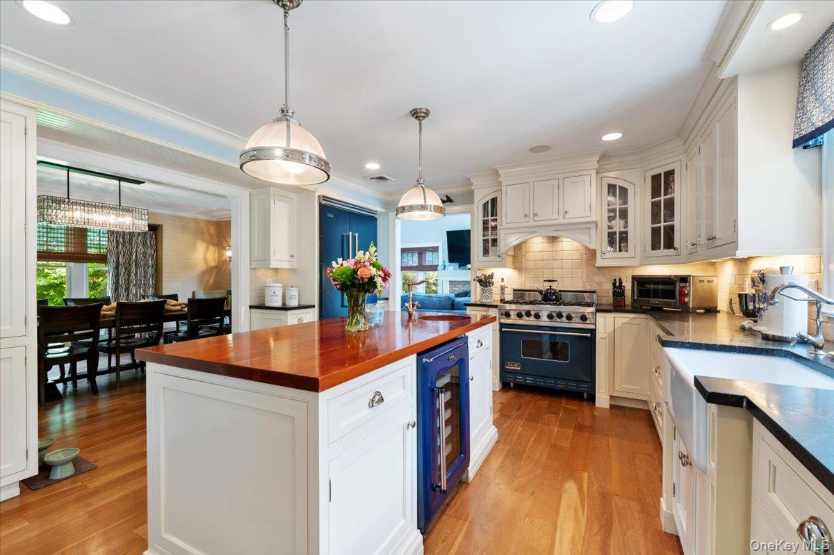 5 Fox Hunt Court Cold Spring Harbor, NY 11724 - Photo 14 of 42 Kitchen featuring a hardwood floor, white cabinetry, and a central island with a wood countertop and built-in beverage refrigerator