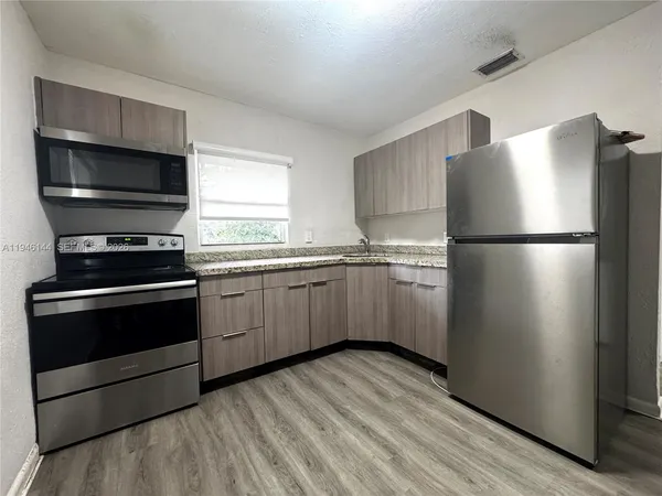 a kitchen with a refrigerator stove and wooden floor