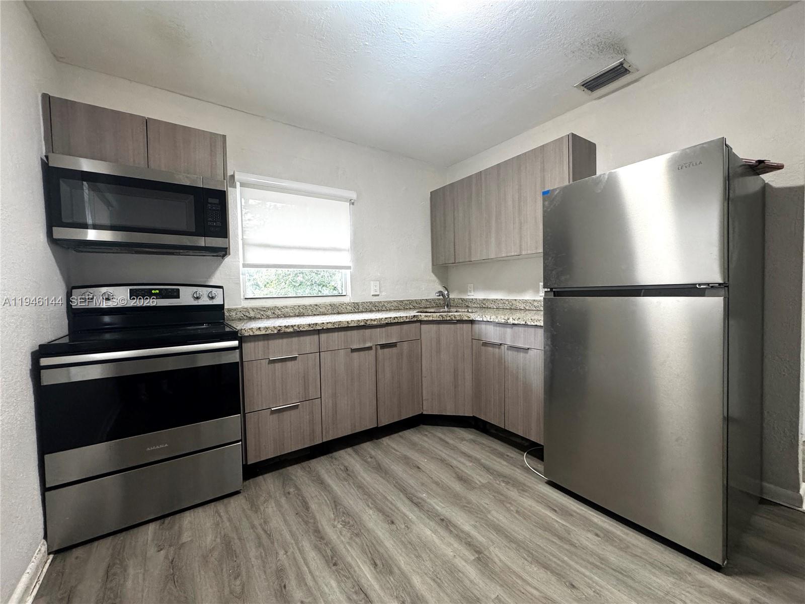529 Southwest 3rd Street, Unit 2 Miami, FL 33130 - Photo 2 of 10 a kitchen with a refrigerator stove and wooden floor