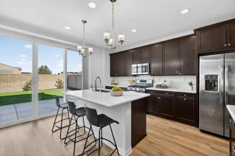 a kitchen with stainless steel appliances kitchen island granite countertop a stove a sink dishwasher a refrigerator and a dining table with wooden floor