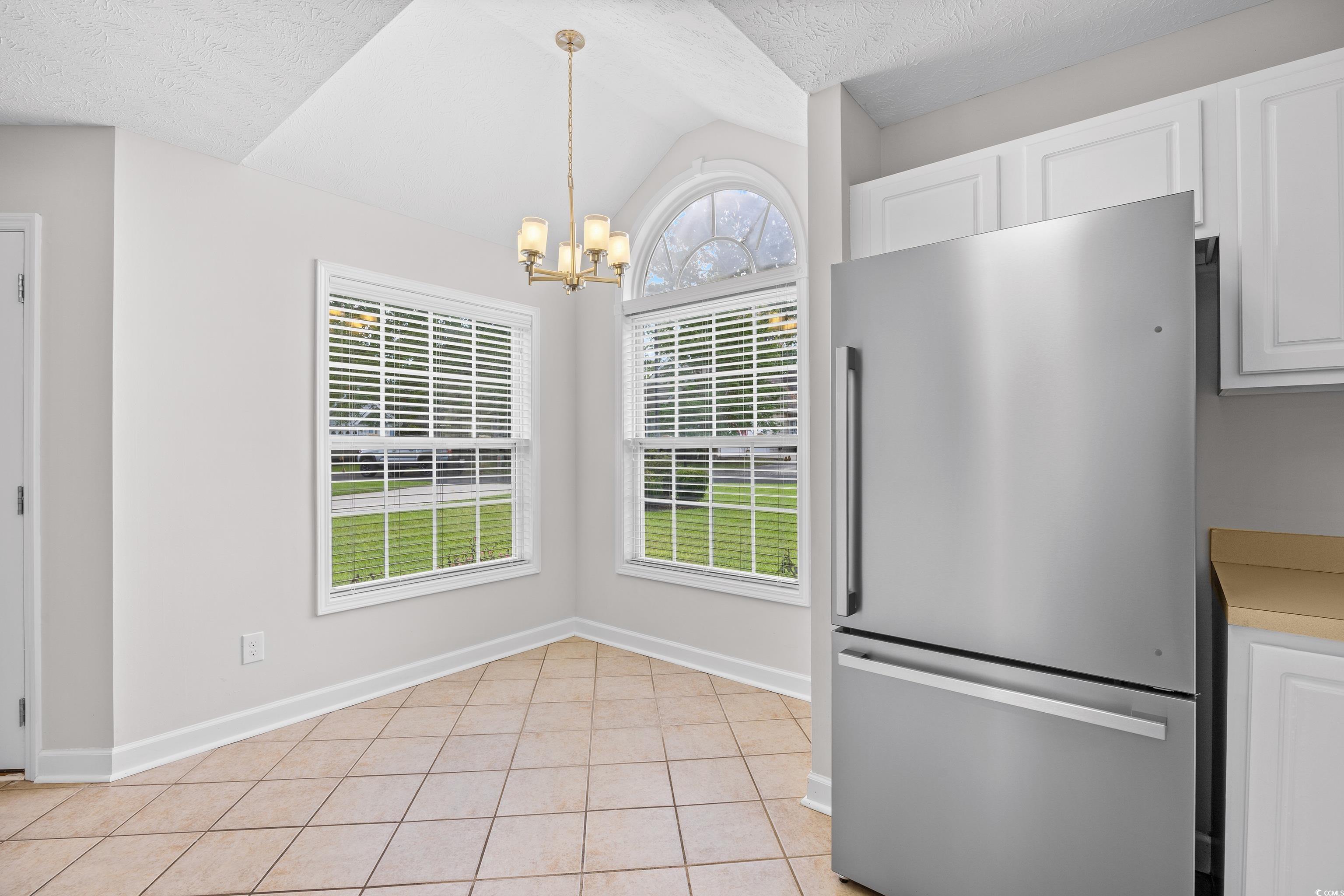 596 Oakmont Drive Myrtle Beach, SC 29579 - Photo 11 of 40 Unfurnished dining area with a chandelier, lofted ceiling, a textured ceiling, and light tile patterned floors