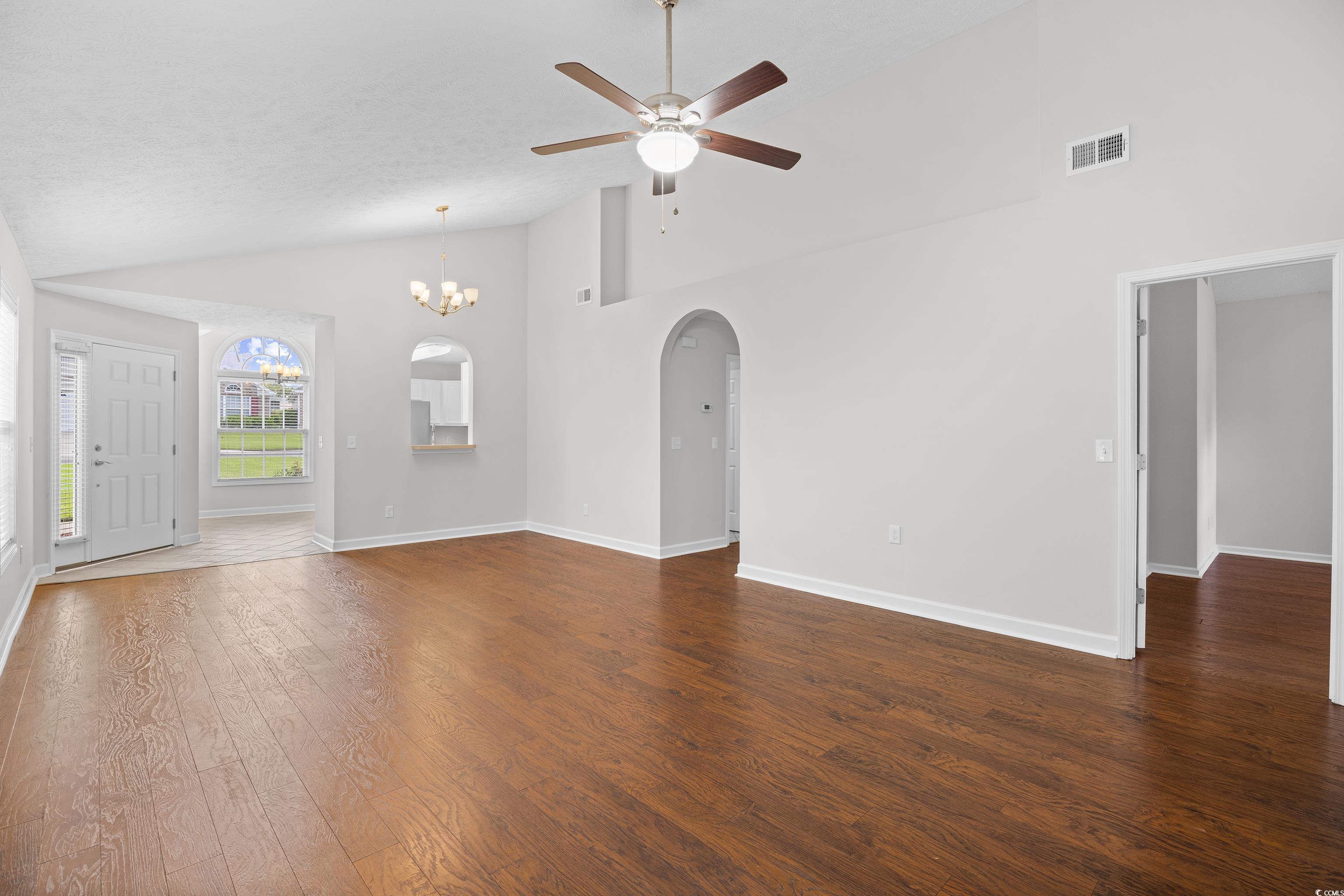 596 Oakmont Drive Myrtle Beach, SC 29579 - Photo 16 of 40 Unfurnished living room with arched walkways, ceiling fan, high vaulted ceiling, dark wood-style floors, and a chandelier