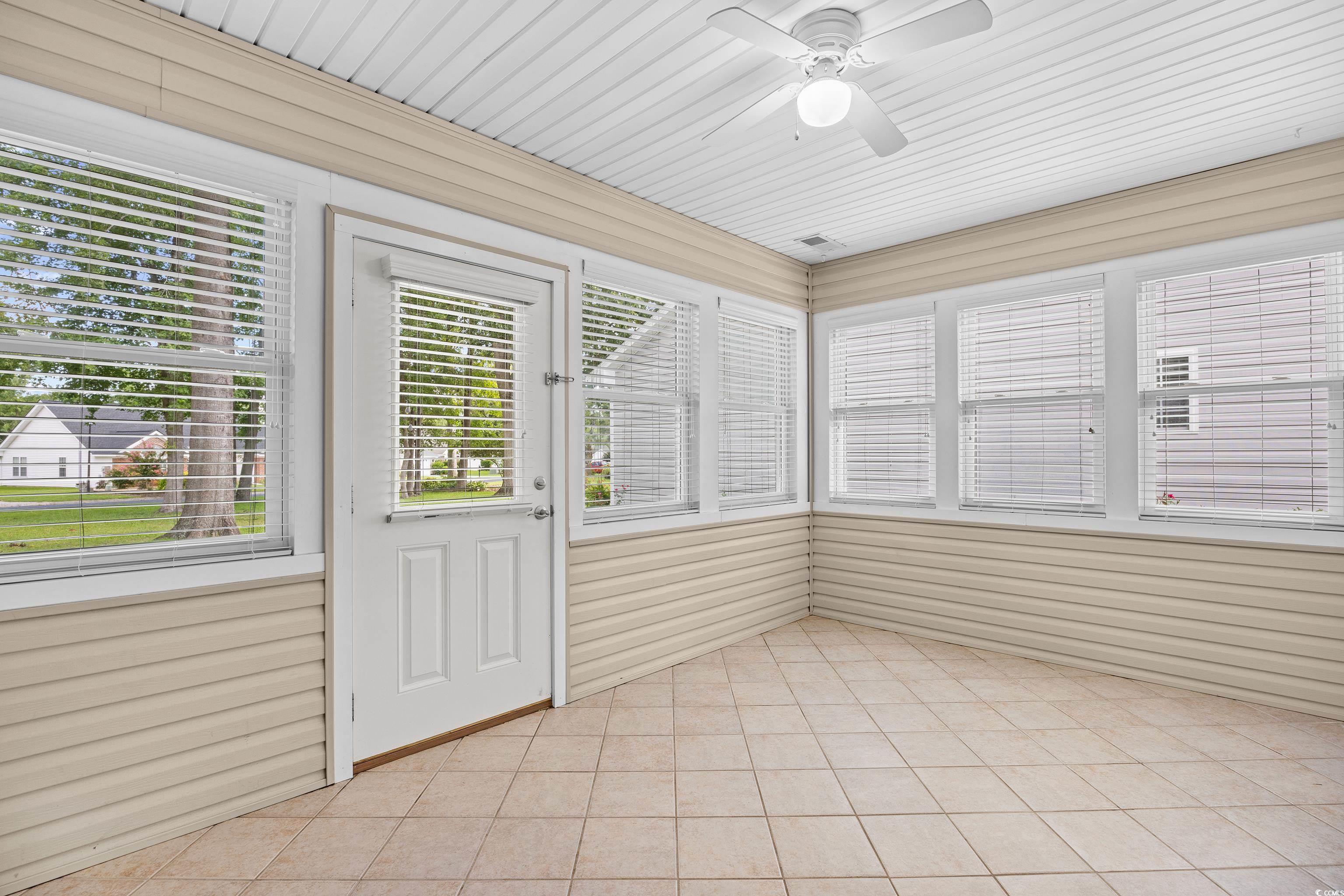 596 Oakmont Drive Myrtle Beach, SC 29579 - Photo 32 of 40 Unfurnished sunroom with ceiling fan, tile patterned flooring, and wooden walls