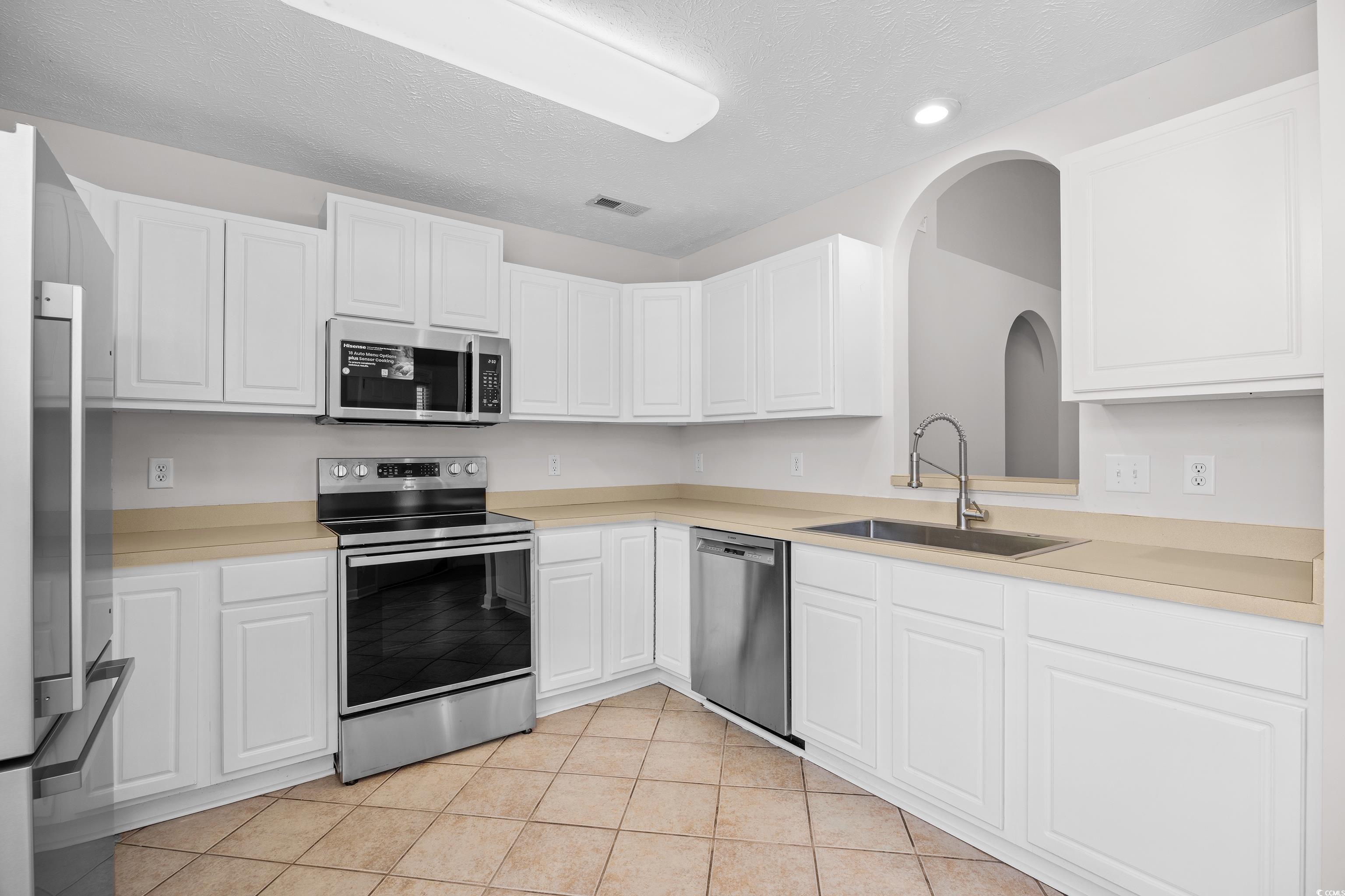 596 Oakmont Drive Myrtle Beach, SC 29579 - Photo 9 of 40 Kitchen featuring appliances with stainless steel finishes, white cabinetry, light countertops, recessed lighting, and light tile patterned flooring