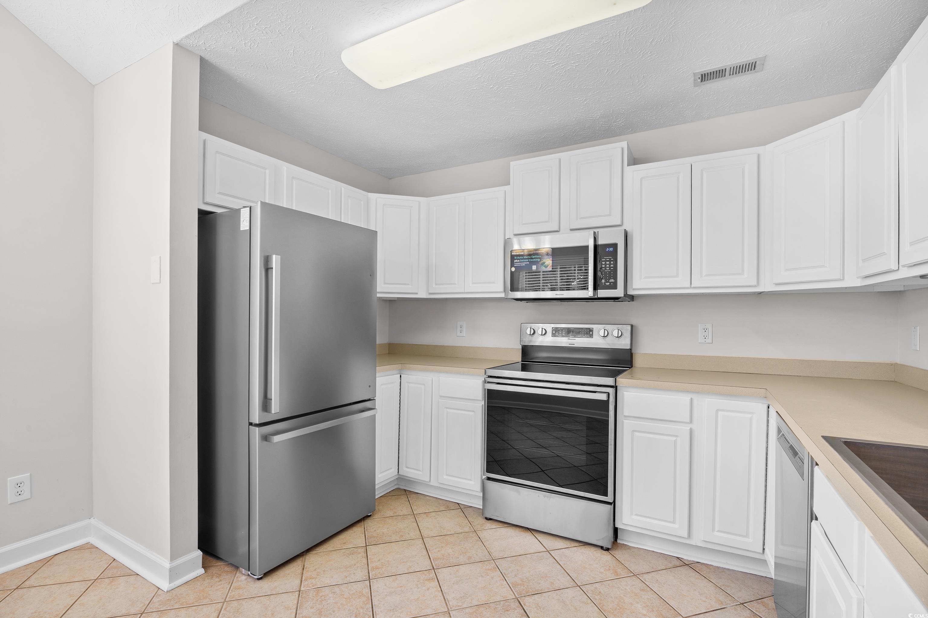 596 Oakmont Drive Myrtle Beach, SC 29579 - Photo 10 of 40 Kitchen featuring stainless steel appliances, white cabinets, light countertops, and light tile patterned floors