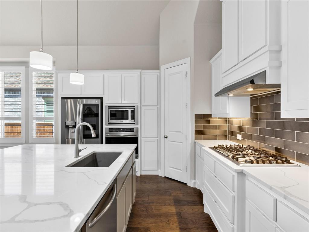 1630 Pebblebrook Lane Prosper, TX 75078 - Photo 14 of 40 a kitchen with stainless steel appliances kitchen island a stove a sink and a refrigerator