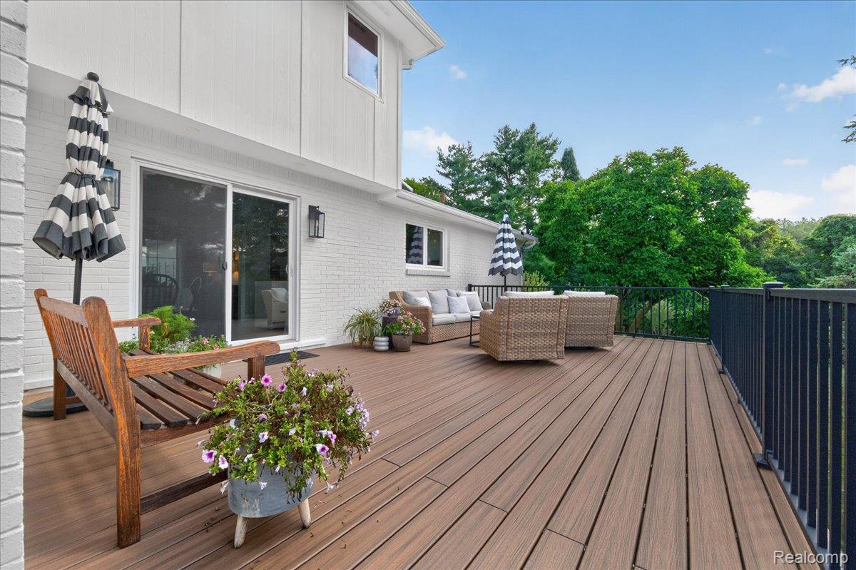 7330 West Gates Street Romeo, MI 48065 - Photo 51 of 73 Expansive outdoor deck with wood-finish composite decking, black metal railings, and a sliding glass door entry