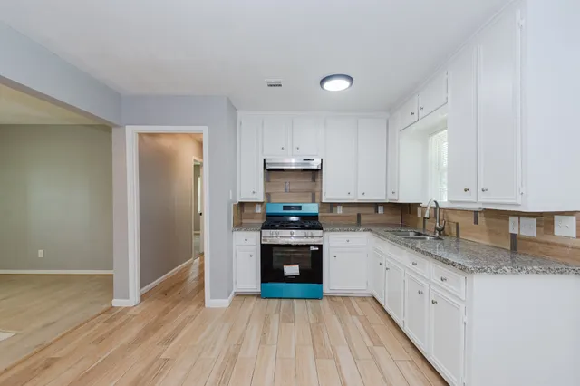 a kitchen with granite countertop white cabinets and stainless steel appliances