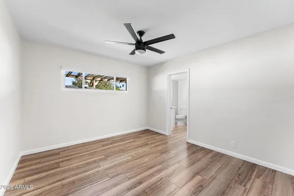 an empty room with wooden floor ceiling fan and windows