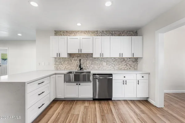 a kitchen with cabinets appliances wooden floor and a window