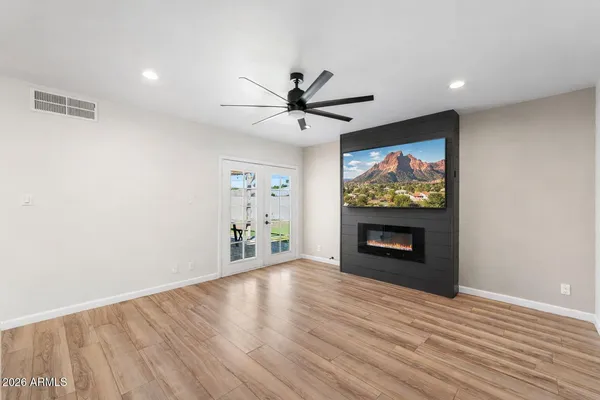 a view of a livingroom with a fireplace a ceiling fan and wooden floor
