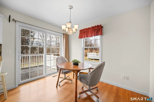 a dining room with wooden floor a chandelier a glass table and chairs