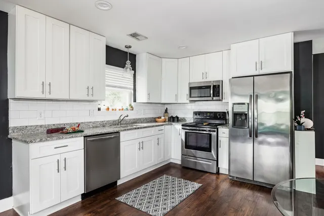a kitchen with granite countertop a refrigerator stove and sink
