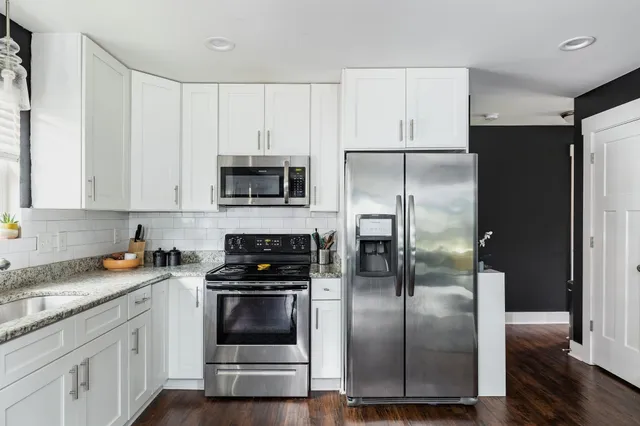 a kitchen with refrigerator a microwave a sink and cabinets