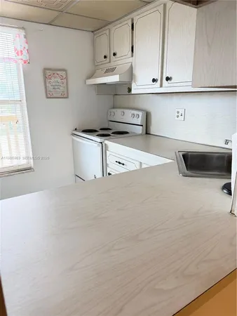 a kitchen with white cabinets and a stove with wooden floor