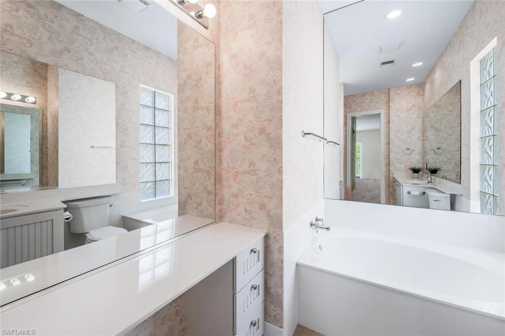 8511 Alessandria Court Naples, FL 34114 - Photo 21 of 45 a bathroom with a tub a sink and a large mirror